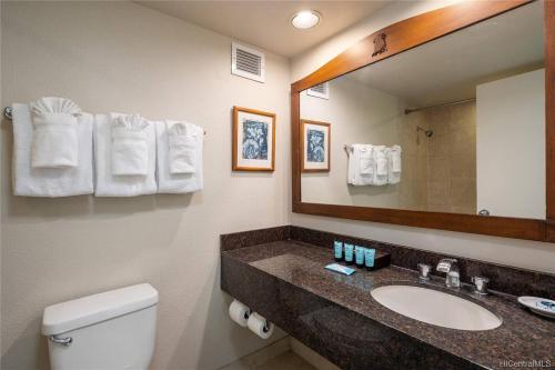 Un baño con lavabo, espejo e inodoro. en Luana Waikiki Oceanview High Floor Condo 1210, en Honolulu