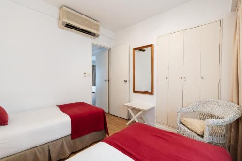a bedroom with a bed and a chair and a mirror at Loi Flats Buenos Aires in Buenos Aires