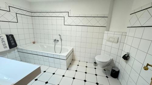 a white tiled bathroom with a tub and a toilet at Pension Arthur in Meißen