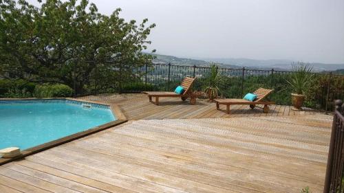 une terrasse en bois avec deux chaises et une piscine dans l'établissement Cosy Home with nice view, home-video, library and piano - 40 min from Grand Bornand & La Clusaz - 50 min - Megève - 10 minutes Le Semnoz, à Quintal