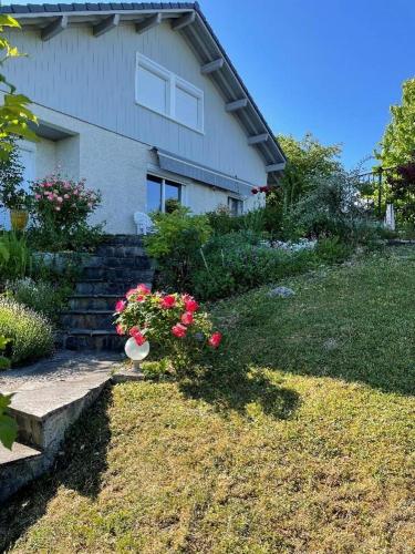 une maison avec un vase de fleurs dans la cour dans l'établissement Cosy Home with nice view, home-video, library and piano - 40 min from Grand Bornand & La Clusaz - 50 min - Megève - 10 minutes Le Semnoz, à Quintal