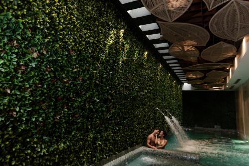 two people standing in a pool in front of a green wall at The Reef 28 Hotel & Spa - Luxury Adults Only - All Suites - With Optional All Inclusive in Playa del Carmen