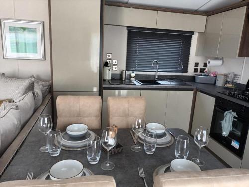a kitchen with a table with plates and wine glasses at Beechwood 20 in Camber