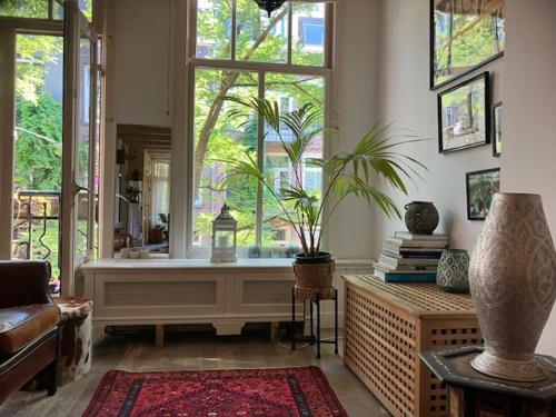 アムステルダムにあるBohemian loftの大きな窓と植物のあるリビングルーム