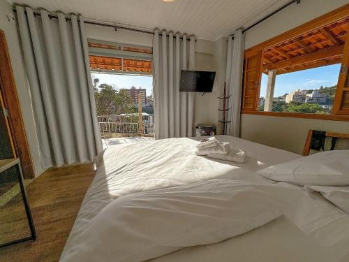 a bedroom with a large white bed and a window at Pousada Ar da Montanha in Serra Negra