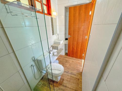 a bathroom with a toilet and a glass shower at Pousada Ar da Montanha in Serra Negra