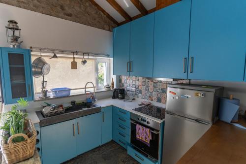a kitchen with blue cabinets and a stainless steel refrigerator at Cantinho do Bairro Alto in Alijó