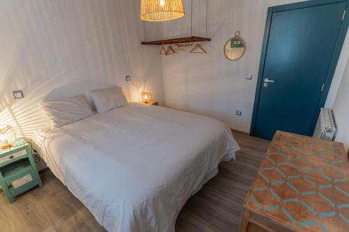 a bedroom with a white bed and a blue door at Cantinho do Bairro Alto in Alijó