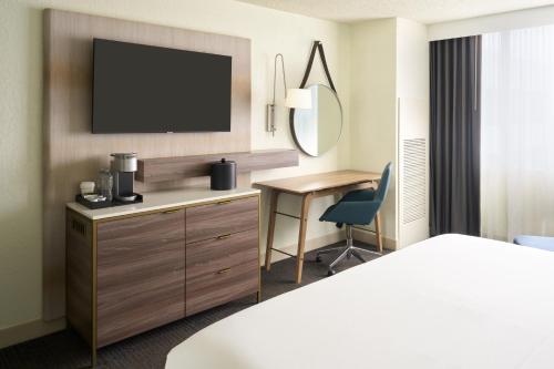 une chambre d'hôtel avec un lit, un bureau et une télévision dans l'établissement Delta Hotels by Marriott West Palm Beach, à West Palm Beach