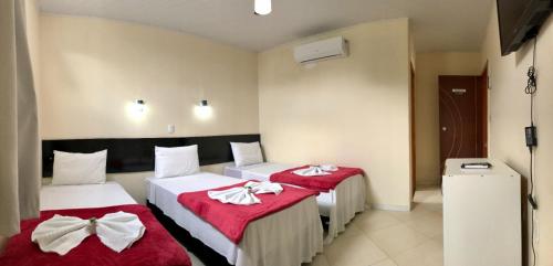 2 camas en una habitación de hotel con sábanas rojas y blancas en Imperial Hotel Amargosa, en Amargosa