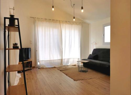 a living room with a black couch and a window at Jolie suite baignée de lumière in Châteauneuf-Val-Saint-Donat