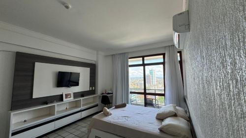 a bedroom with a bed and a tv and a window at Flat Gold Beach in Recife