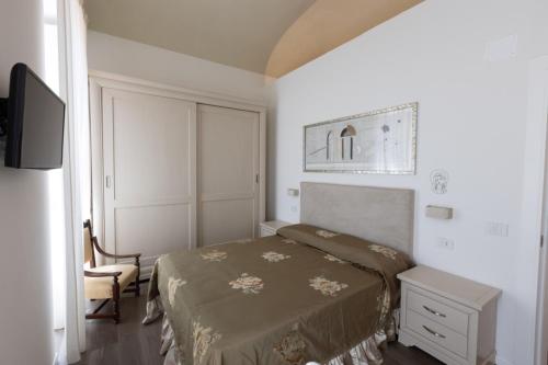 a bedroom with a bed and a chair and a television at Suite Piazza del Popolo in Ascoli Piceno