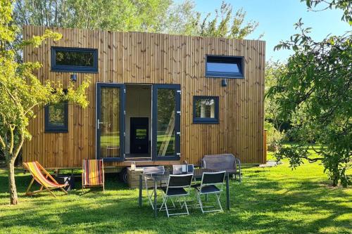 une petite maison avec une table et des chaises dans la cour dans l'établissement Le petit nid des Mésanges, à Volckerinckhove