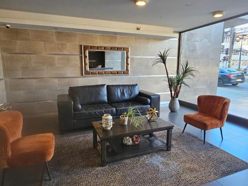 a living room with a black leather couch and chairs at Departamento Centro Osorno in Osorno