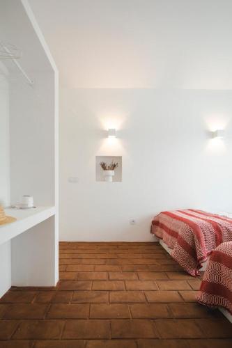 a bedroom with white walls and a bed with a red blanket at Vagar do Pastor in Alandroal