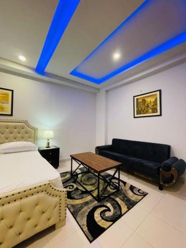 Un dormitorio con una cama, un sofá y una mesa. en Elegant 2 Bed Apartment Tranquil Stays, en Islamabad