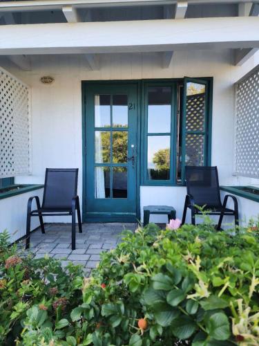 two chairs sitting on a patio with a door at Auberge des Nuages in La Malbaie
