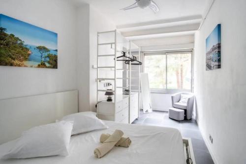 une chambre blanche avec un lit et une chaise dans l'établissement PASTEUR - Bel appartement familial Pharo -plage des Catalans, à Marseille