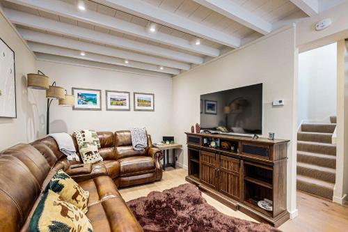 a living room with a leather couch and a television at Modern Mountain Getaway in Olympic Valley