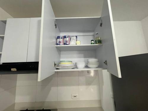 a white kitchen with white cabinets and dishes on shelves at Fabuloso Apto Club House Piscina Sauna Turco y mucho más in Ricaurte