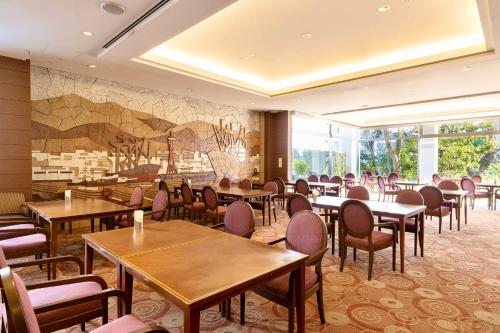 a restaurant with tables and chairs and a mural at Hotel Kitano Plaza Rokkoso in Kobe