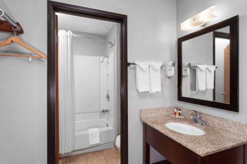 a bathroom with a sink and a tub and a mirror at Super 8 by Wyndham Sun Prairie/Madison E in Sun Prairie
