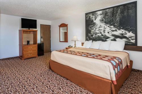 a hotel room with a large bed and a tv at Super 8 by Wyndham Gillette in Gillette