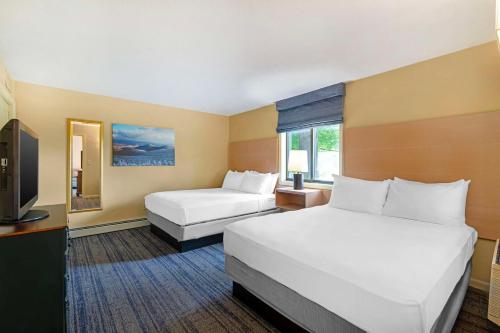 a hotel room with two beds and a television at Best Western Inn & Suites Rutland-Killington in Rutland