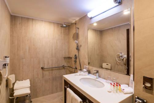 a bathroom with a sink and a large mirror at Ramada Hotel & Suites by Wyndham Yerevan in Yerevan
