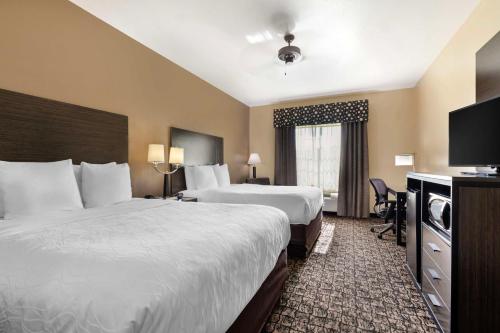 a hotel room with two beds and a television at Best Western Carthage Inn & Suites in Carthage
