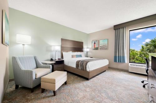 a hotel room with a bed and a chair and a window at Best Western Intracoastal Inn in Jupiter