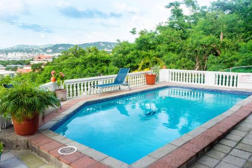 a swimming pool with a chair on a white fence at Cleopatra Villas - Sea View in Rodney Bay Village