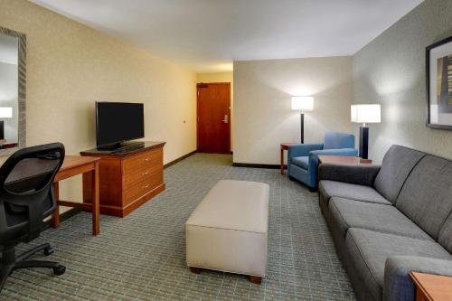 a hotel room with a couch and a tv and a desk at Drury Inn & Suites Grand Rapids in Cascade