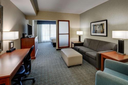 a hotel room with a couch and a desk and a living room at Drury Inn & Suites Grand Rapids in Cascade