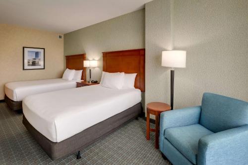 a hotel room with two beds and a chair at Drury Inn & Suites Grand Rapids in Cascade