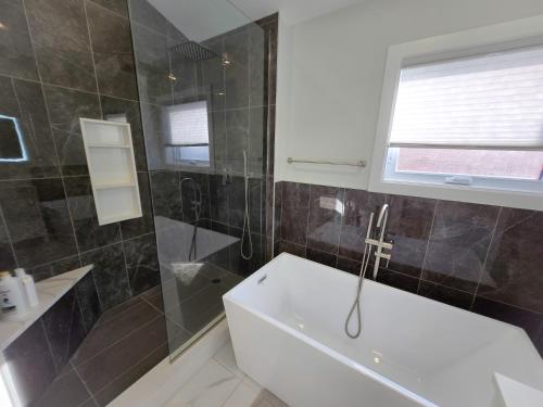 a bathroom with a tub and a shower and a sink at Byward-Market Luxury GuestHouse in Ottawa