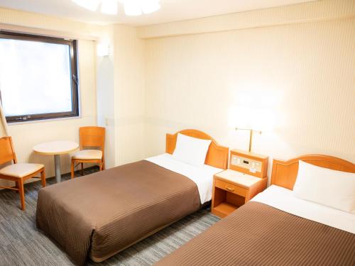 a hotel room with two beds and a table and a window at Numazu Grand Hotel in Numazu