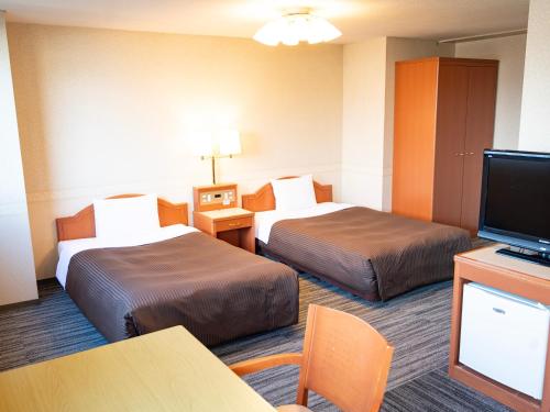 a hotel room with two beds and a flat screen tv at Numazu Grand Hotel in Numazu