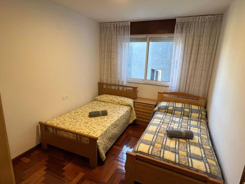 two beds in a small room with a window at Ático Calvo Sotelo 217 in Sarria