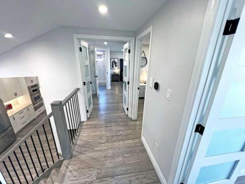 a hallway of a home with a staircase and white walls at Luxe Home Near Limeridge - Sleeps 11 - Pool in Hamilton