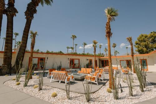 a patio with chairs and palm trees in front of a building at Mojave Resort - Adults Only in Palm Desert