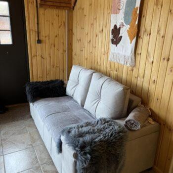 a white couch in a room with a wooden wall at Maja saunaga kahele Arturis in Rõmeda