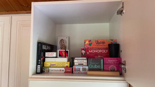 a shelf filled with books on top of a cabinet at Modernt gästhus med två sovrum och sovmöjlighet för upp till fem personer in Ekerö