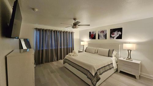 a white bedroom with a bed and a ceiling fan at Sunny Oasis with private pool in Homestead