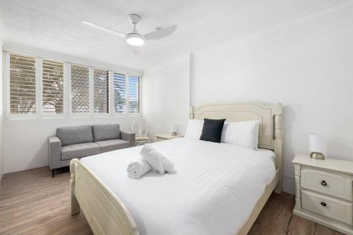 Un dormitorio con una gran cama blanca y un sofá. en Beachfront Beauty - Cooly, en Gold Coast