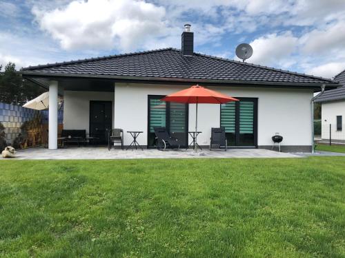 a house with a patio with a red umbrella at Ferienhaus SeenSuchtLausitz in Großräschen