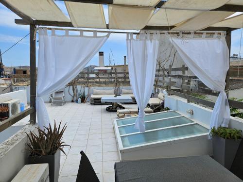 a patio with white drapes and a hot tub at stone house classic in Ermoupoli