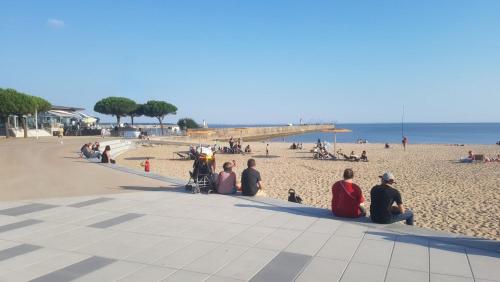 un groupe de personnes assises sur une plage dans l'établissement Appartement hyper-centre, à Saint-Nazaire