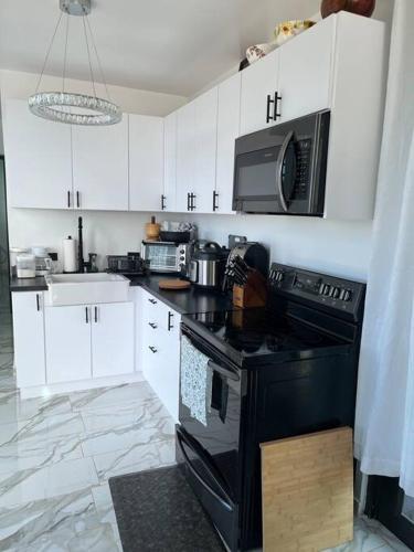 a kitchen with white cabinets and a black stove top oven at ONE BEDROOM Ocean- Mountain View home five min to beach in Luquillo